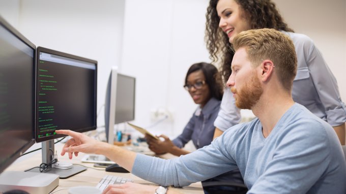 Students and teacher looking at code on computer screen